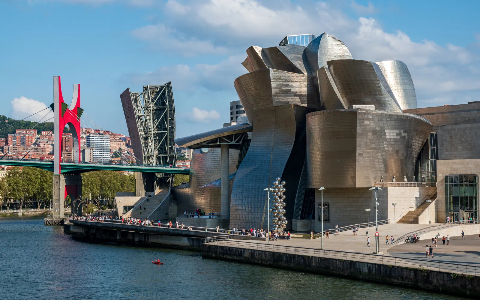 The Guggenheim Museum Bilbao on the Nervión river, with the red arch of La Salve bridge on the left