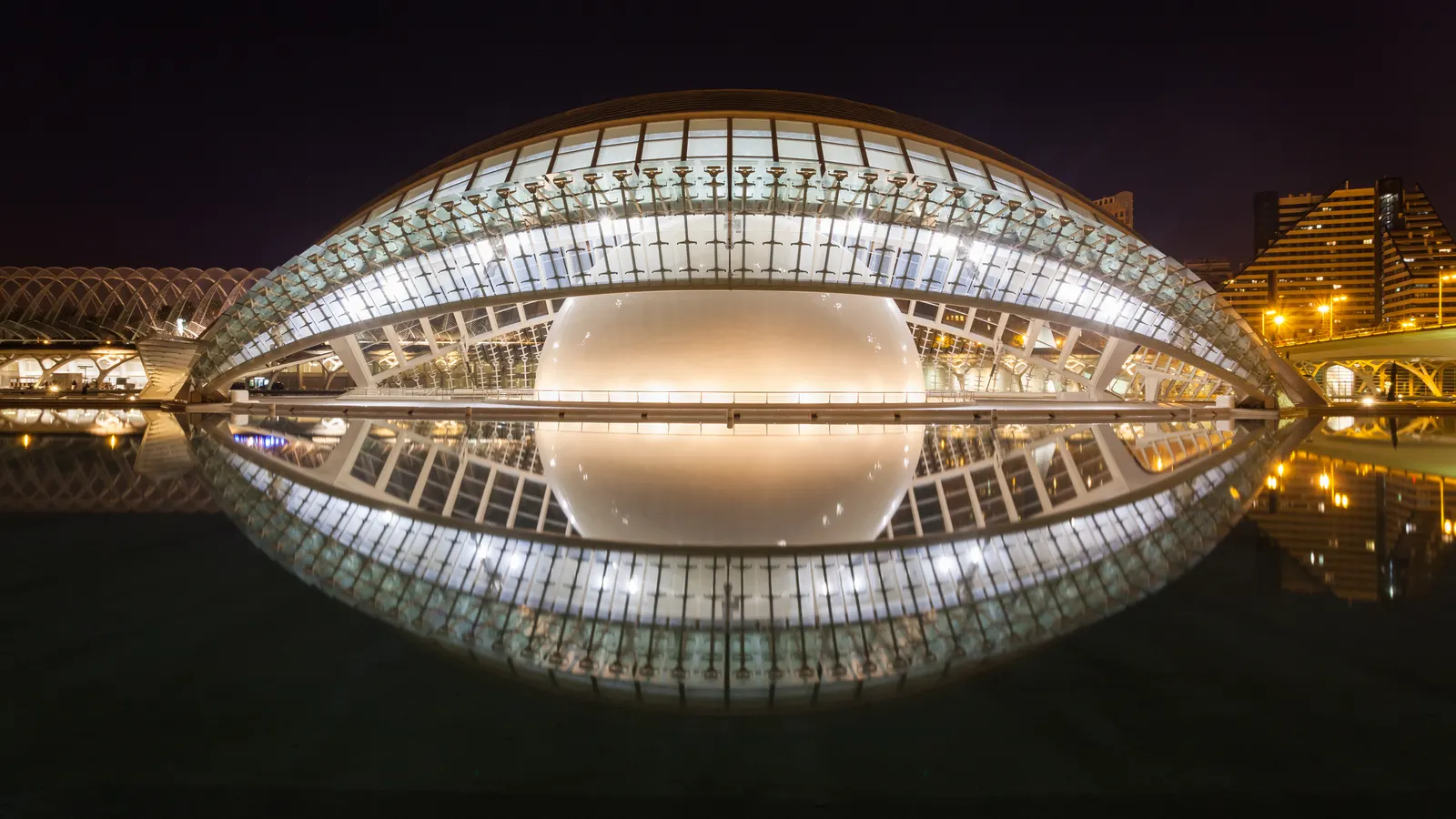 The Hemisfèric at the City of Arts and Sciences, lit at night and reflected in its pool
